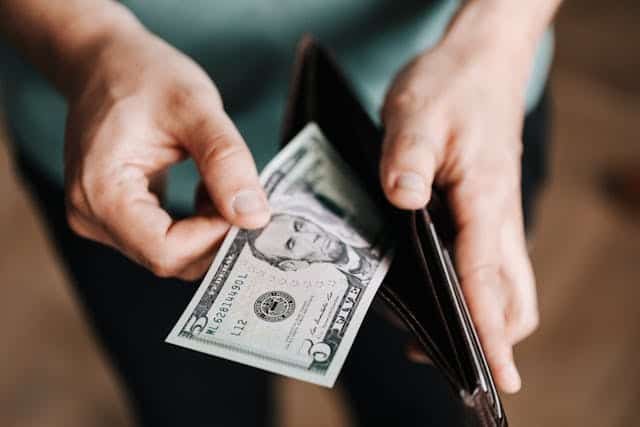 Man holding an open wallet with little money